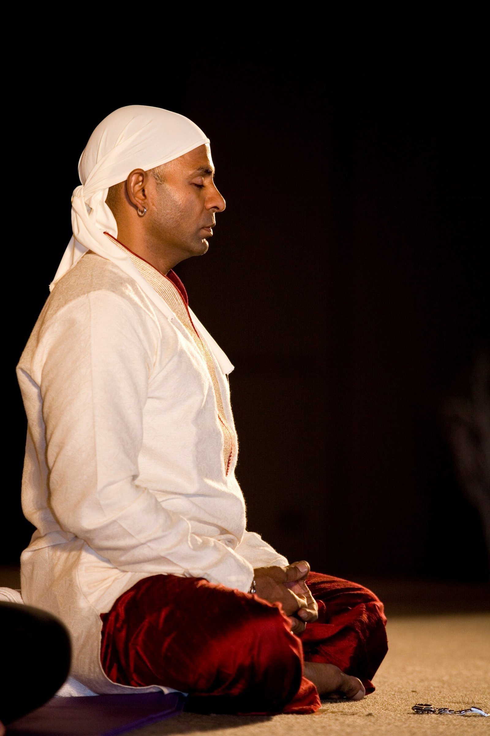 A man sitting on the ground in a white outfit