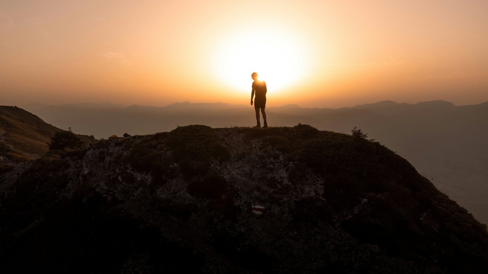 a man standing on top of a mountain at sunset