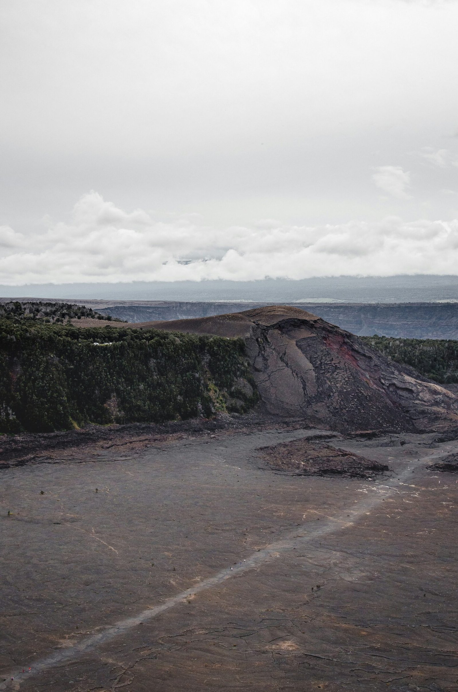 brown and green mountain beside sea under white clouds during daytime